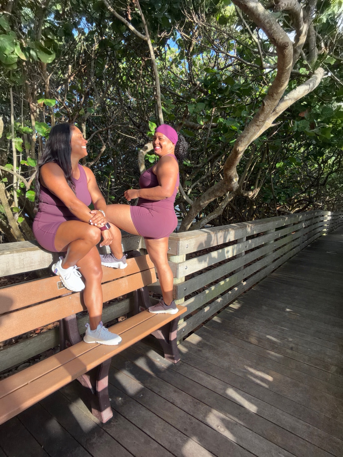 Kat and Peg laughing together on a sunny boardwalk bench
